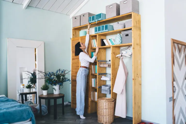 Young female standing on tiptoes reaching for storage box